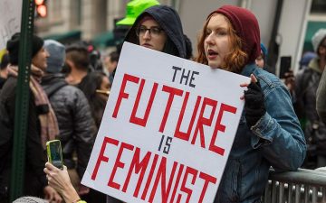 2 people holding the sign the future is feminist