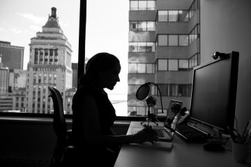 Silhouette of a woman working at her computer with a city view visible in the background