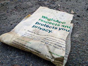 Dirty, ripped newspaper on ground with headline "WhatsApp respects and protects your privacy"